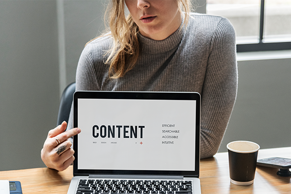 Focused woman developing a content strategy on her laptop in a minimalist setting, displaying 'CONTENT' on the screen.